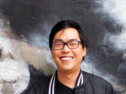 Kevin Lo smiling in front of a mural