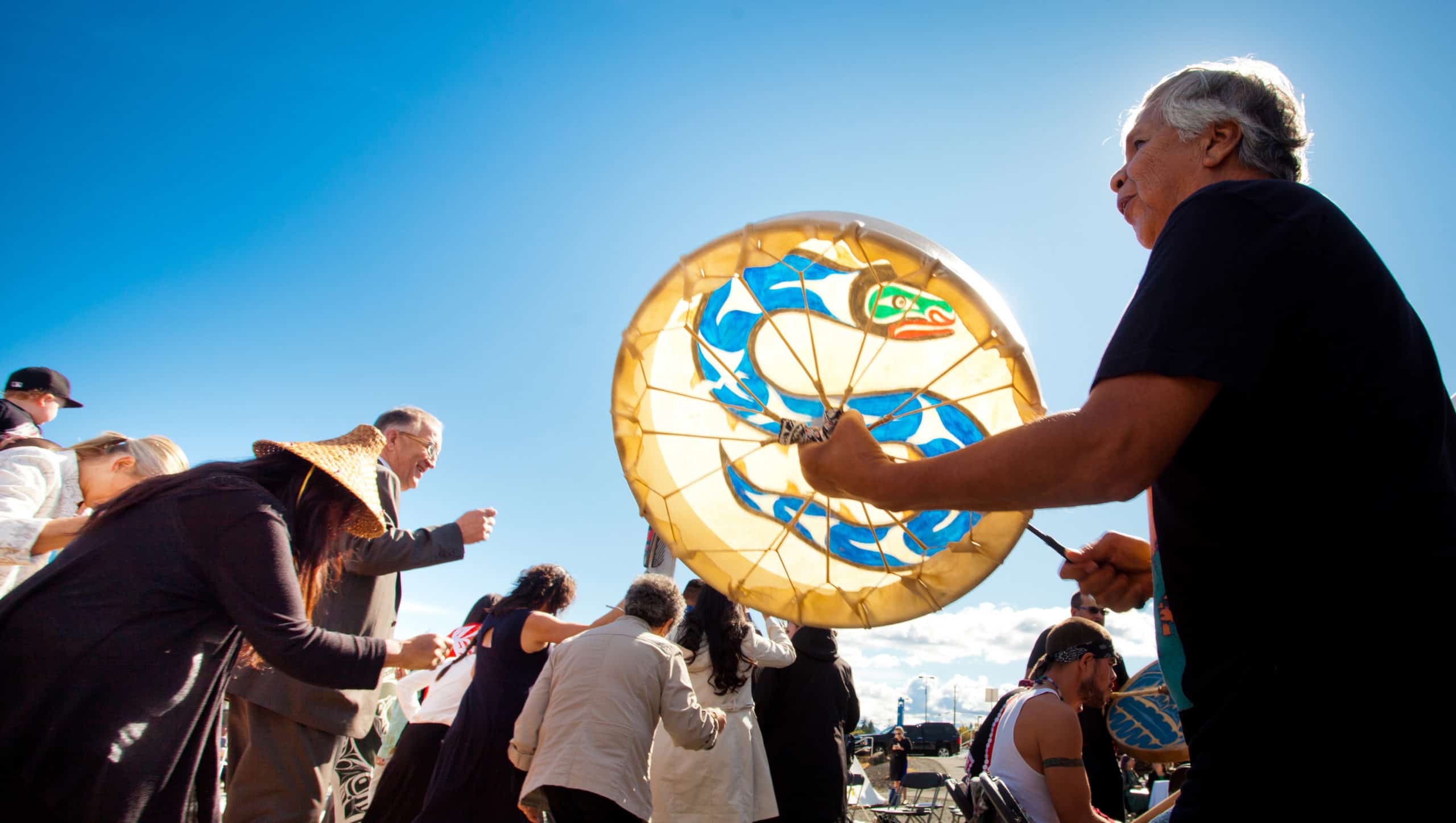 Person holding a drum with several people in the distance.