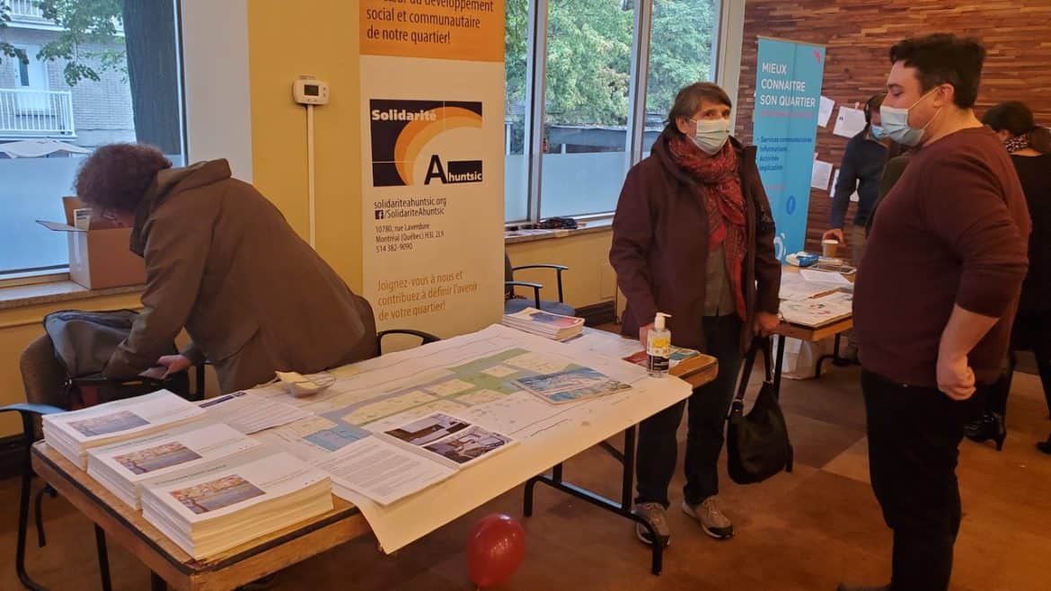 Individuals in masks at a booth with a sign for Solidarité Ahuntsic