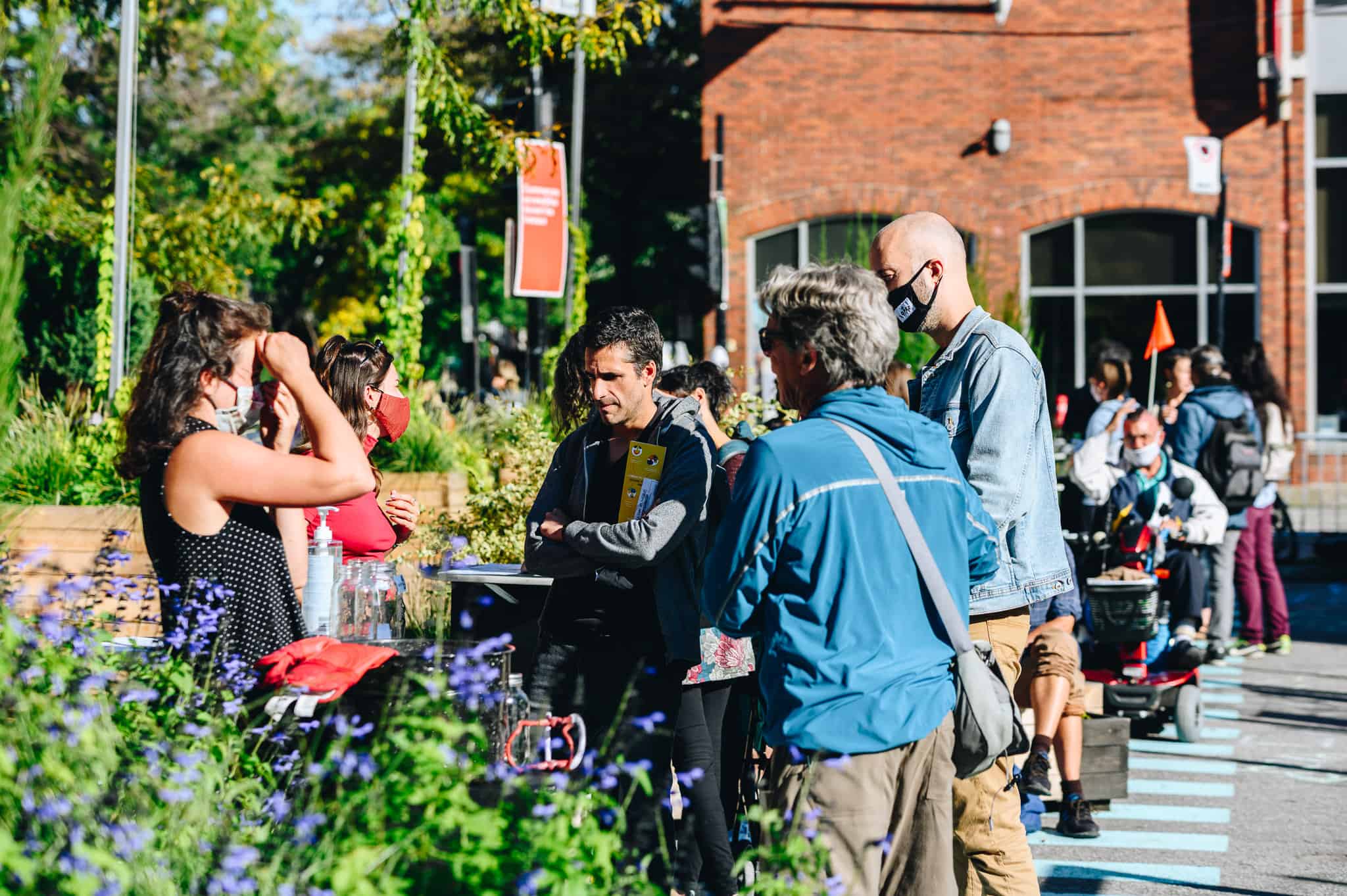 People gathering outdoors on a sunny day talking..
