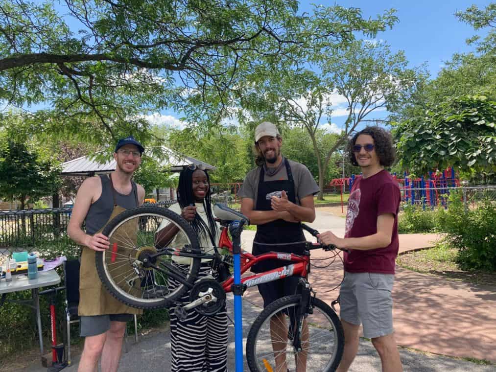 Four people smiling around a bike on a repair stand.
