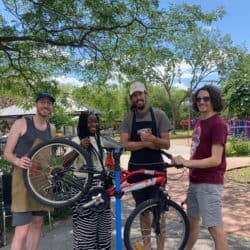 Four people smiling around a bike on a repair stand.