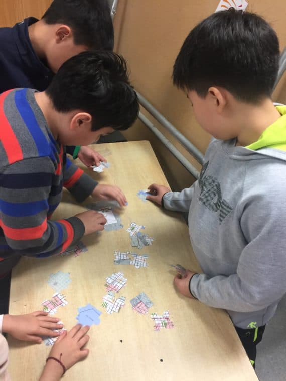 Children around a table, assembling a puzzle.