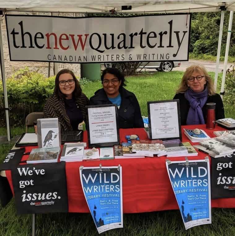 Staff and volunteers at a booth for The New Quarterly. The booth includes a sign for The New Quarterly and many books on the table.