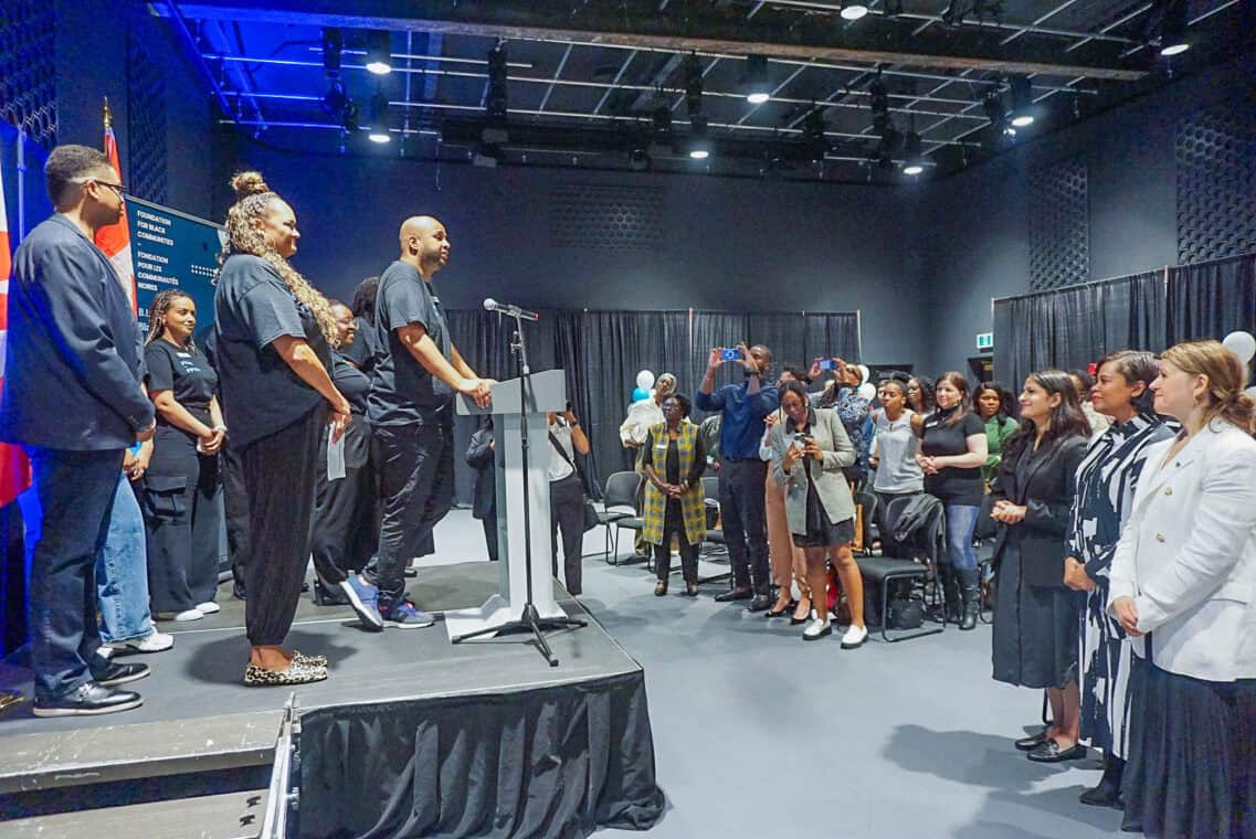 A group standing on stage with one person at the mic speaking to the crowd.