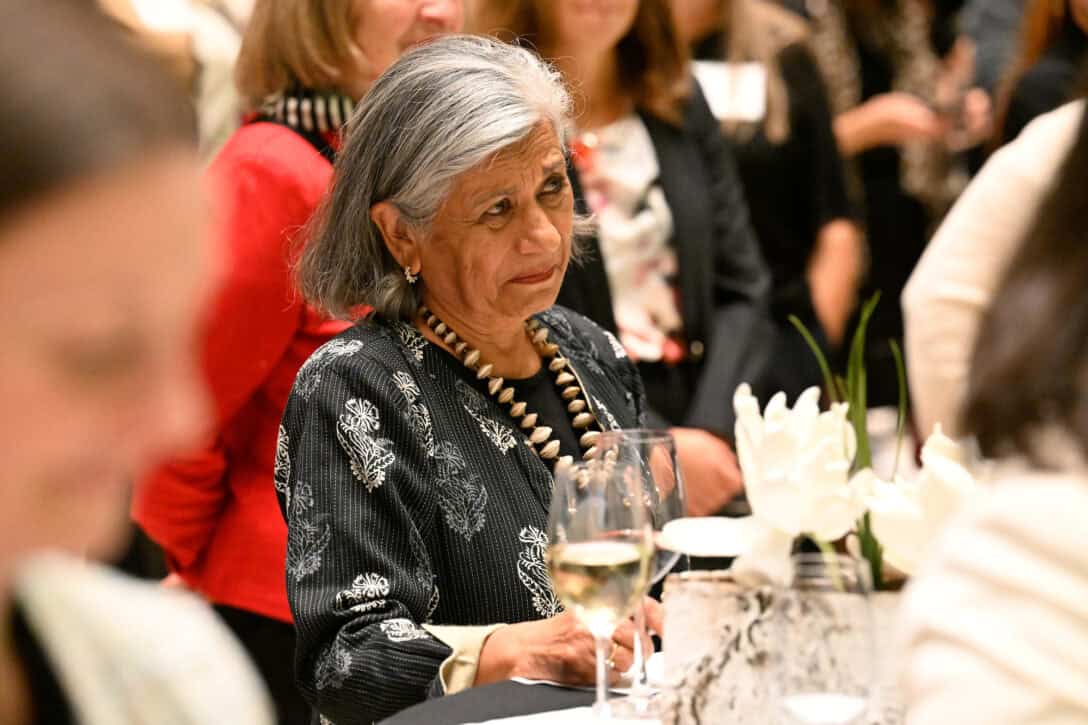 Ratna Omidvar sitting at a table with others listening to someone speaking.