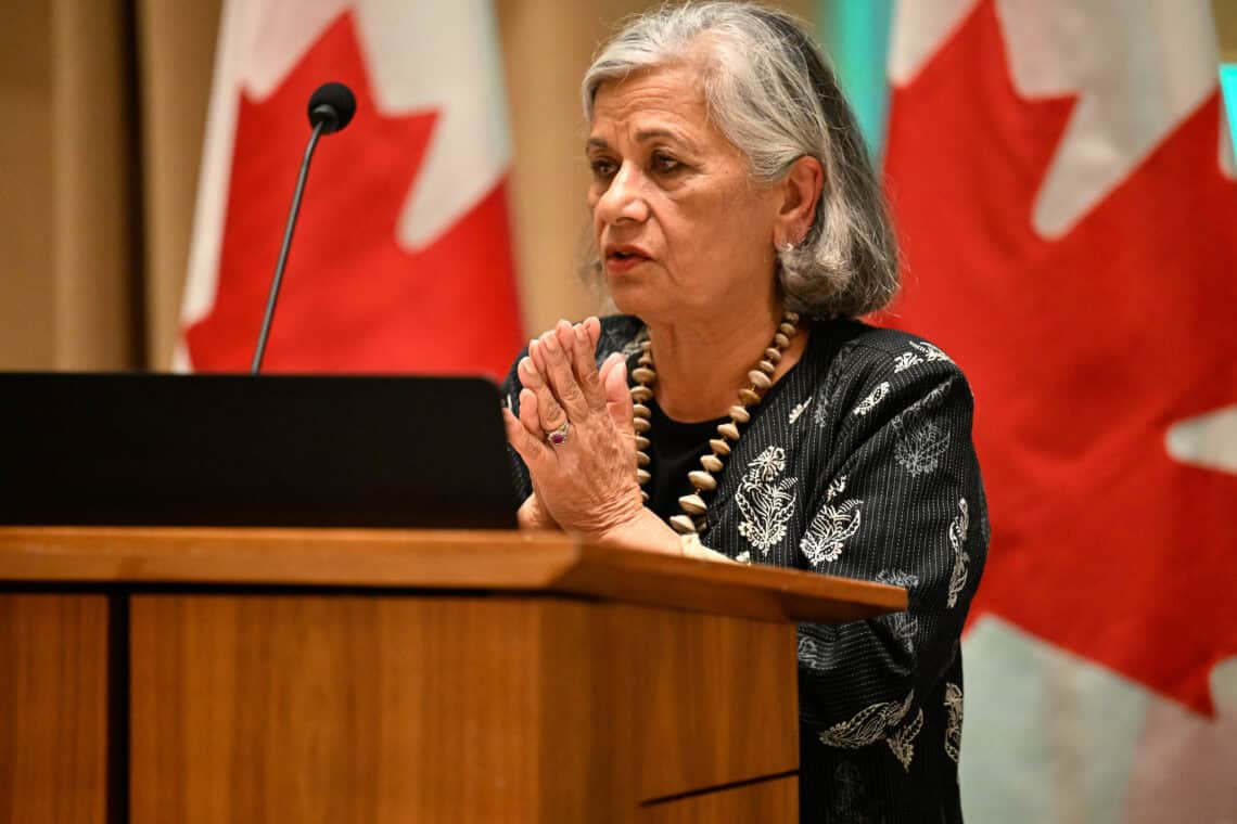 Ratna Omidvar stands at a podium with her hands clasped.