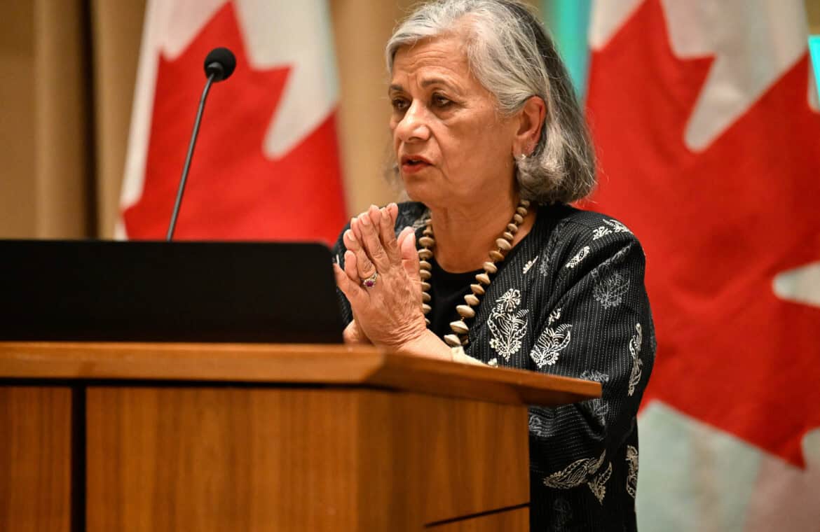 Ratna Omidvar stands at a podium with her hands clasped.