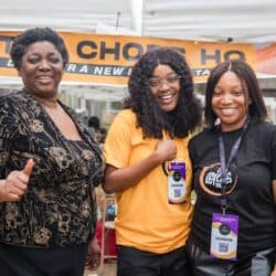 Three women posing with smiles. Two are wearing conference tags that say "vendor."
