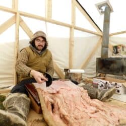 Nicholas Flowers in Inotsiavik’s tupik, cleaning a sealskin with an ulu.