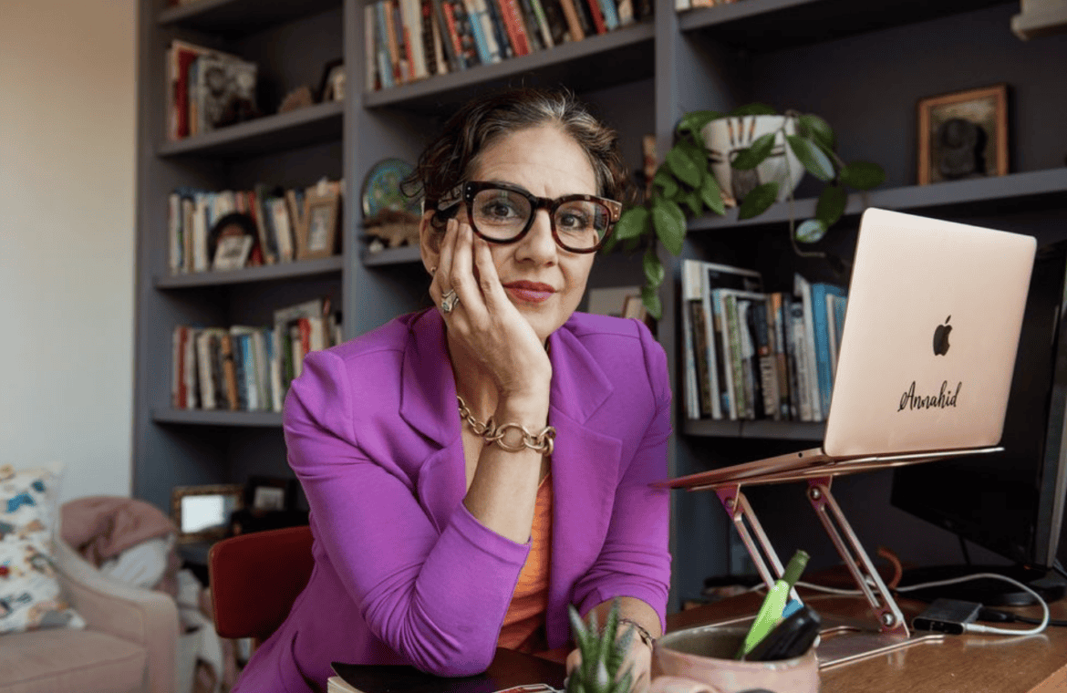 Photo of Annahid Dashtgard sitting at a desk in front of her laptop.