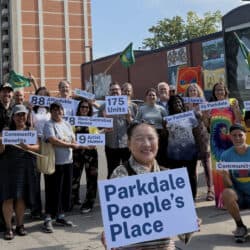 A photo of smiling members of the Parkdale Neighbourhood Land Trust in front of Parkdale People's Place.
