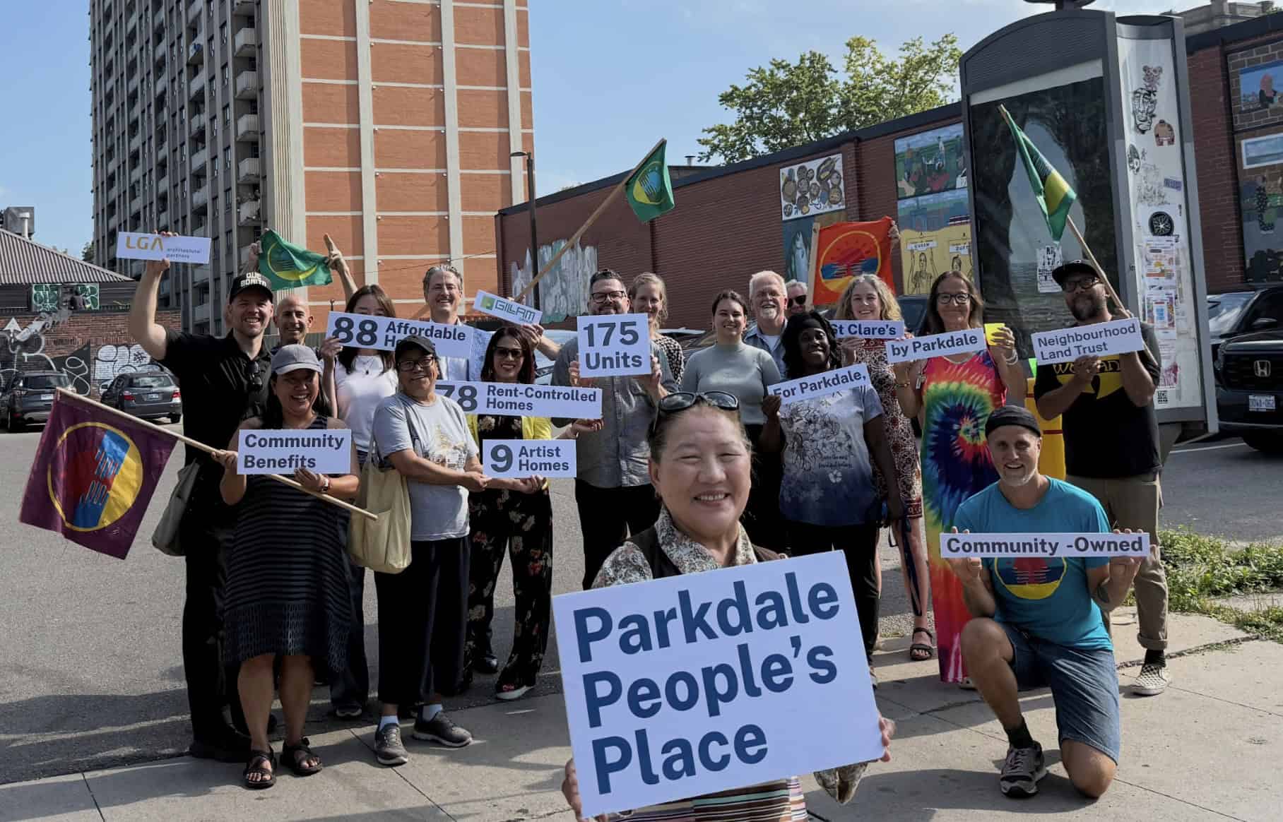 A photo of smiling members of the Parkdale Neighbourhood Land Trust in front of Parkdale People's Place.