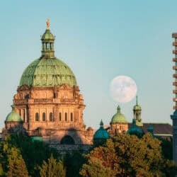 A photo of the moon rising over the Parliament Buildings in Victoria, BC, during sunset.
